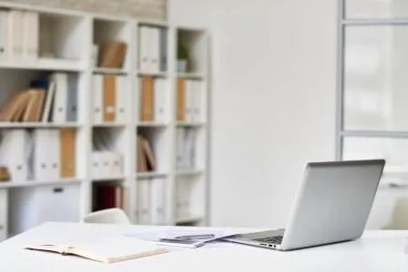 Clean, modern bookkeeper's desk with laptop, books, and files, illustrating Harvest Real Estate Group's comprehensive services in loans and refinancing.