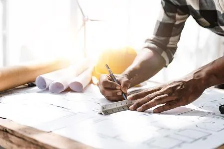 Contemporary architect's table with plans, embodying Harvest Real Estate Group's commitment to construction services, from remodeling to full home construction.